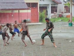 Personel Satgas TMMD Bermain Sepak Bola Bersama Anak-anak Meski Diguyur Hujan